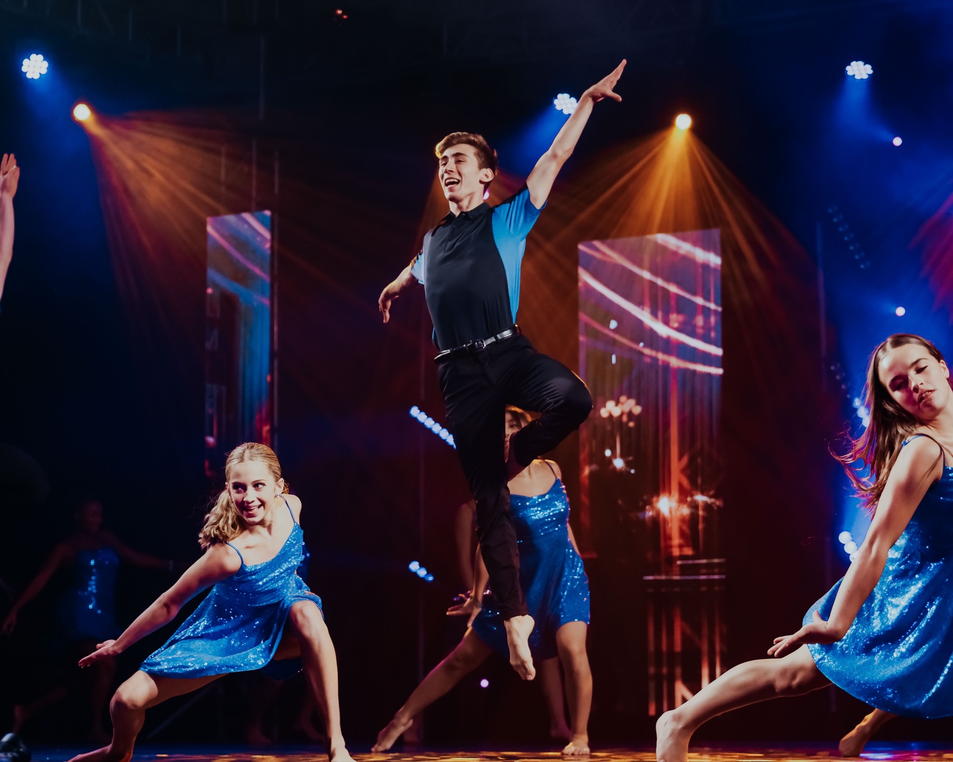 Gala performer leaping on stage under blue and amber lights